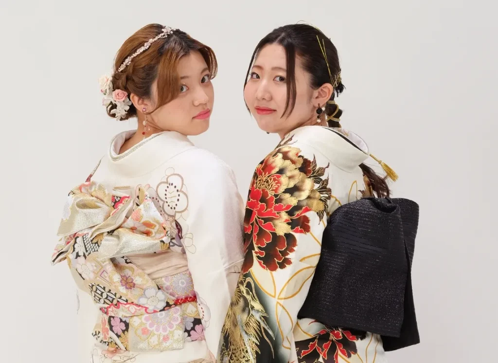 出雲・米子の成人振袖・成人袴のレンタル・白と古典柄の振袖を着て振り向く2人の女性のショット。着付けから撮影までのトータルサポートを表現。